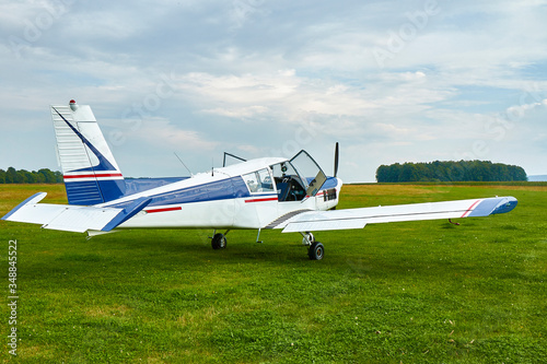 Back view of Zlin Z-43 four-seat airplane standing on a grass runway.  Low-wing monoplane.