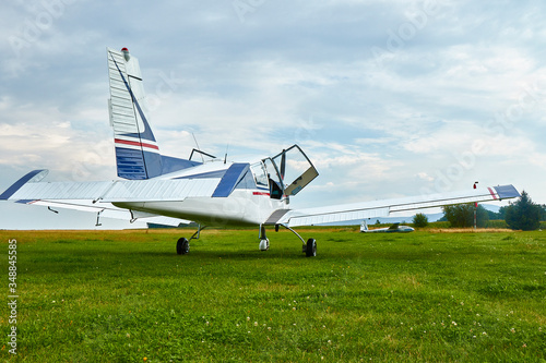 Back view of Zlin Z-43 four-seat airplane standing on a grass runway. Low-wing monoplane.