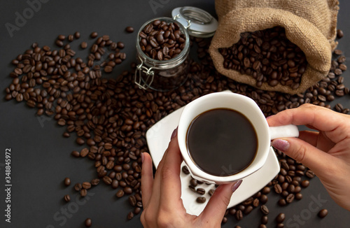 Morning black coffee in a Cup. The woman holds the Cup and inhales the coffee aroma