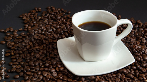 a hot Cup of espresso. It looks perfect in a white Cup on a saucer with coffee beans on a black background © sergey