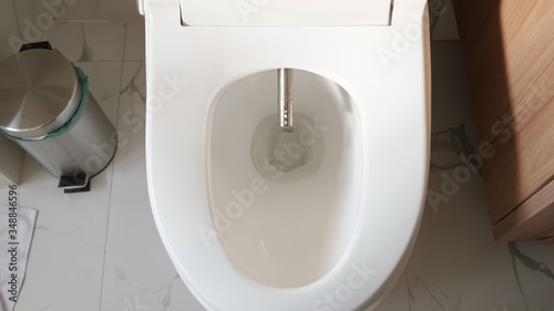 modern silver bidet injector appears in white flush near rubbish bin smart home bathroom close upper view photo
