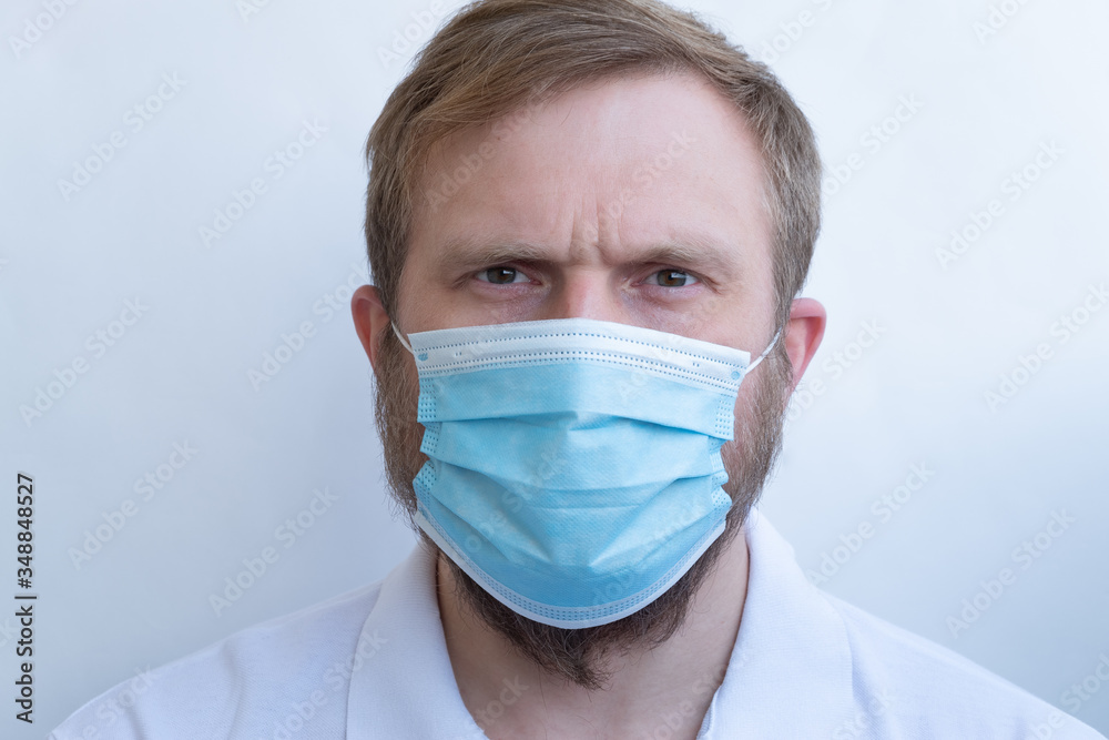 Close-up of a man's face in a protective blue mask. Strict and serious male gaze. Close-up of a man's face in a protective blue mask. Strict and serious male gaze.