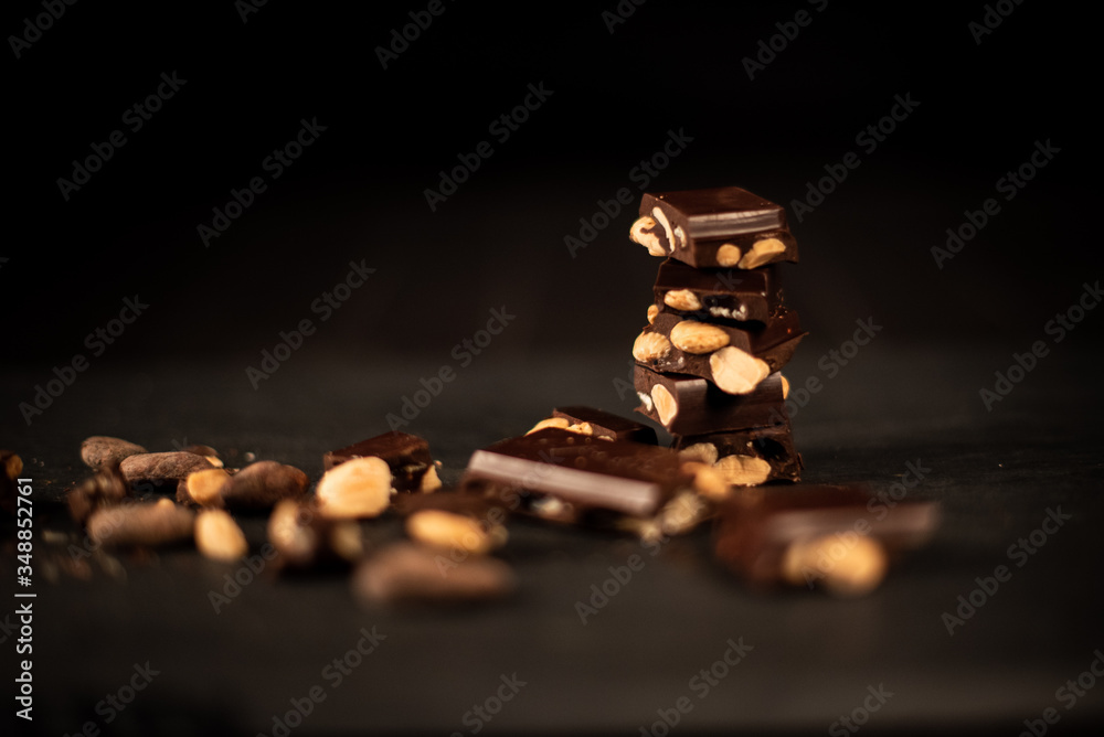 chocolates, dark chocolate with almonds and cocoa powder on slate table with black background 
