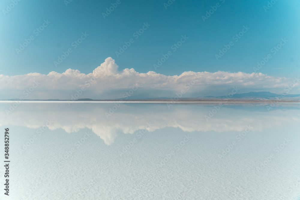 Obraz premium Blue Sky Clouds Mirror Reflection. Cloud Sky reflect on water surface of Bolivia's Salt Flats. Empty space in landscape. Holiday, vacation, freedom scene with horizon. Salar de Uyuni salt flat