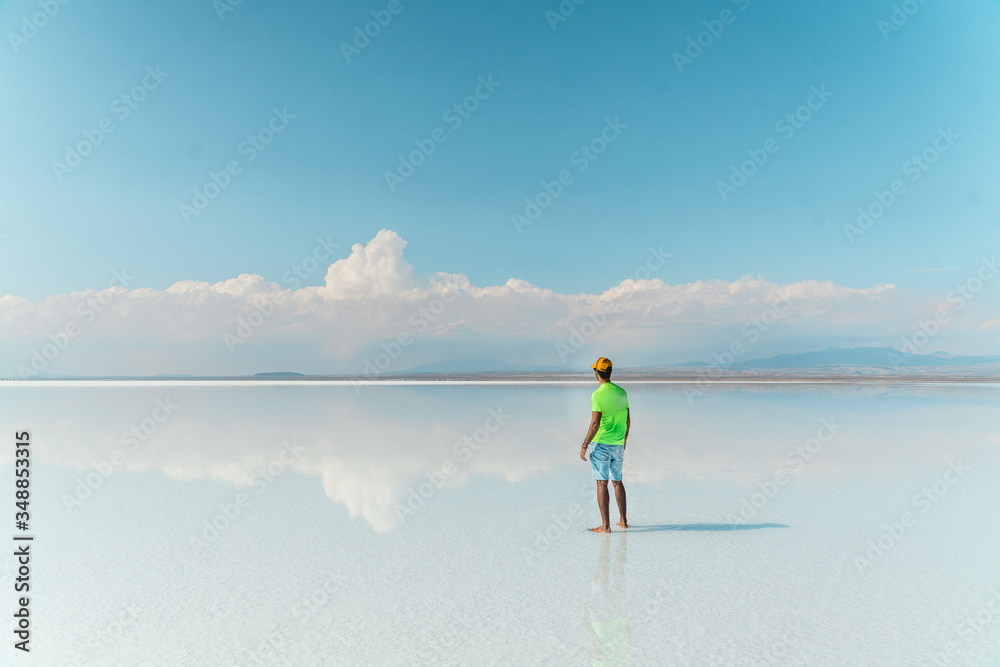 Naklejka premium Travel. Man. Salt Flats Uyuni Bolivia. Tourist on beautiful mirror reflection on blue sky and cloud. DRONE Shot in Salar de Uyuni salt flat. Holiday, love, adventure vacation honeymoon travel