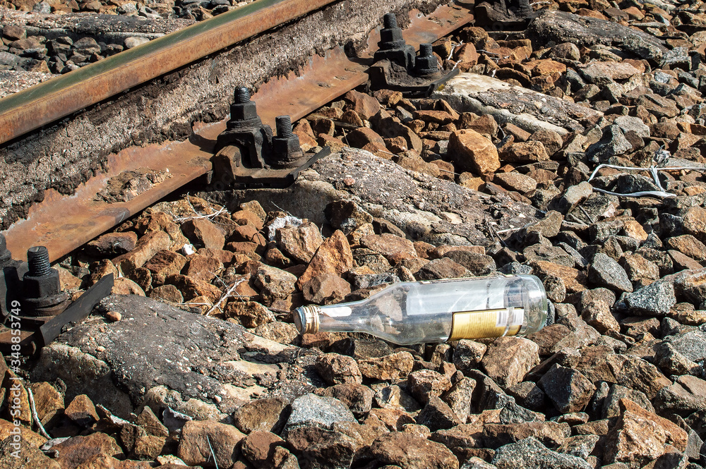 An empty glass alcohol bottle is lying near the railway. Garbage on the railway. Drunkenness among railway workers. An empty glass alcohol bottle is lying near the railway. Garbage on the railway. Drunkenness among railway workers.