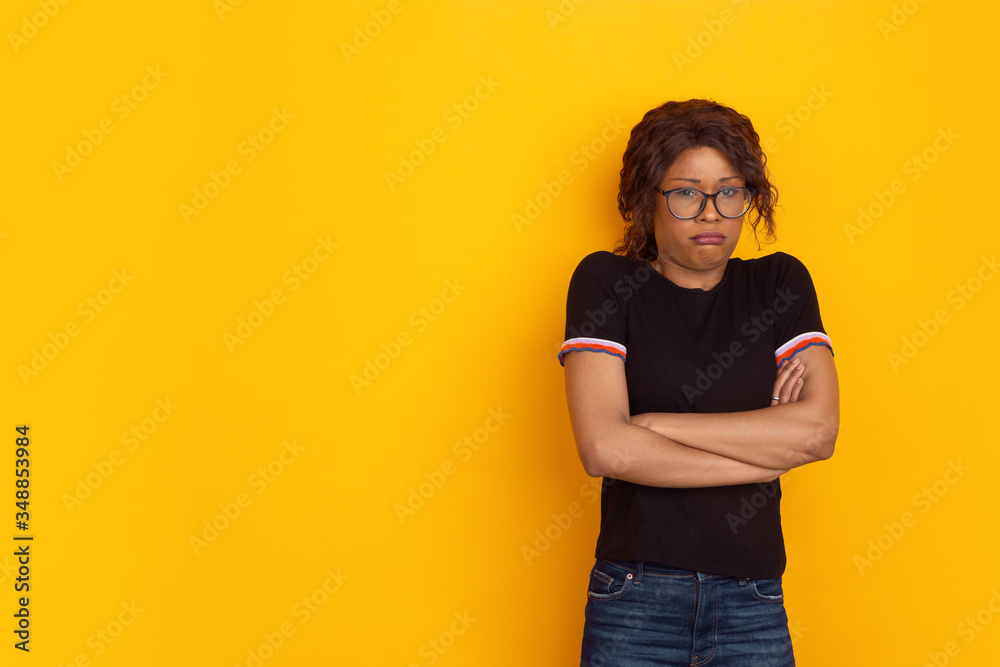 Offended as a child. African-american young woman's portrait isolated on yellow studio background. Beautiful female curly model. Concept of human emotions, facial expression, sales, ad, youth. Offended as a child. African-american young woman's portrait isolated on yellow studio background. Beautiful female curly model. Concept of human emotions, facial expression, sales, ad, youth.