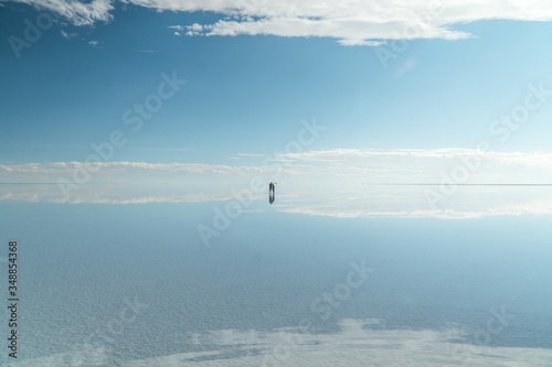 Blue Sky Clouds Mirror Reflection. People. Cloud Sky reflect on water surface of Bolivia's Salt Flats. Empty space in landscape. Holiday, vacation, freedom scene with horizon. Salar de Uyuni salt flat