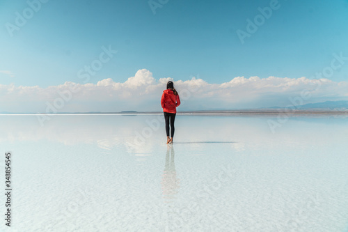 Travel. Woman. Salt Flats Uyuni Bolivia. Tourist girl on beautiful mirror reflection on blue sky and cloud. DRONE Shot in Salar de Uyuni salt flat. Holiday, love, adventure vacation honeymoon travel