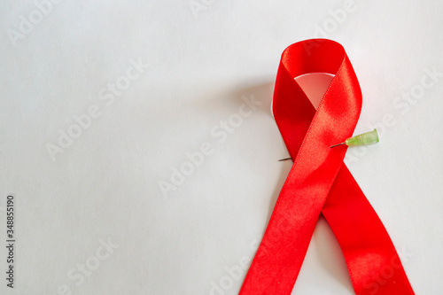 The red ribbon is an international symbol of the fight against AIDS, with a needle on a white background photo