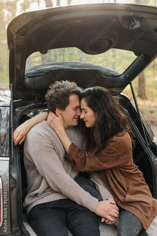 Young beautiful couple relaxing together sitting on a car trunk Young beautiful couple relaxing together sitting on a car trunk