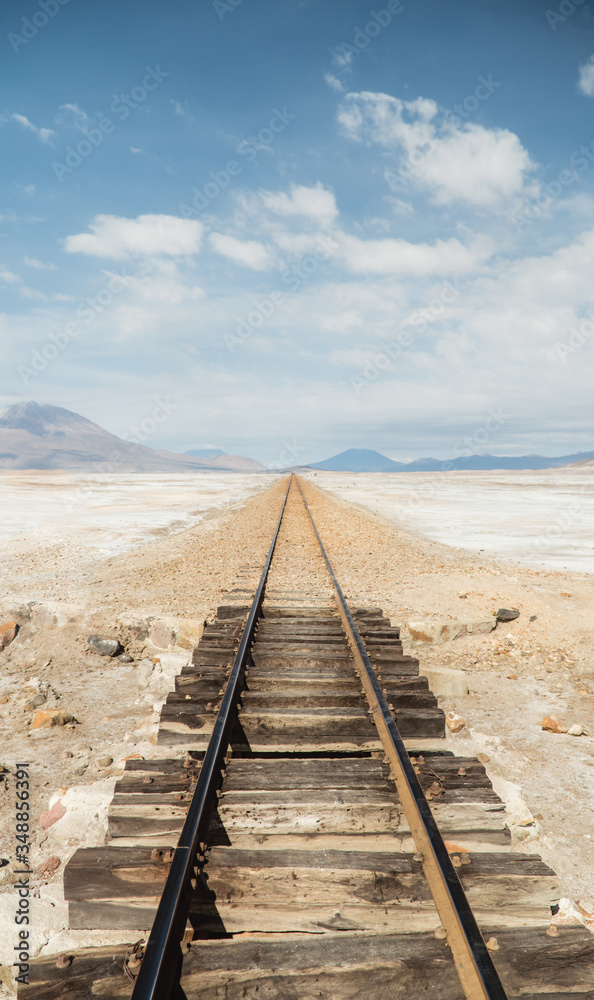 Wooden Train Track Railway lines. Bolivia Salt Flats mountain landscape. Bolivian salty desert and blue sky background. Train Cemetery, Salar de Uyuni. Symmetry, transport, travel, tourism, journey