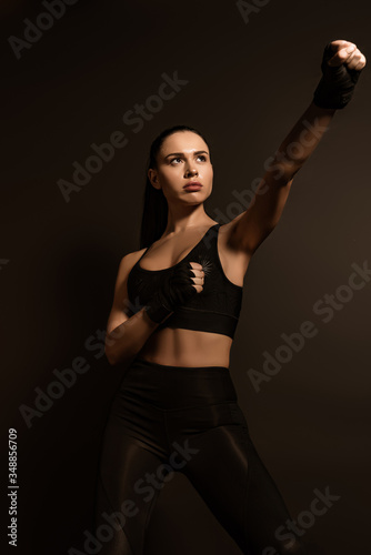 Beautiful sportswoman in sports gloves with outstretched hand isolated on black
