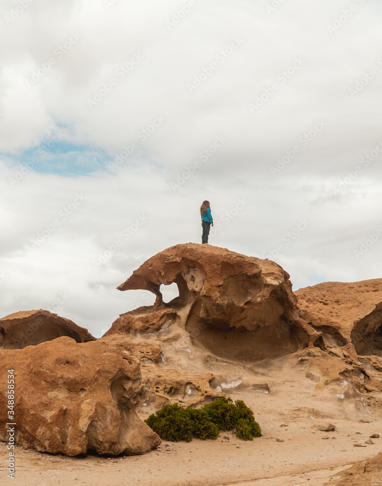 Tourist woman hiking Rocky landscape mountain. Dry, Barren desert, snowcapped mountains wilderness. Mountain range view. Salt Flats, Uyuni, Bolivia. Copy space, Rocks, blue sky, nature, hiker