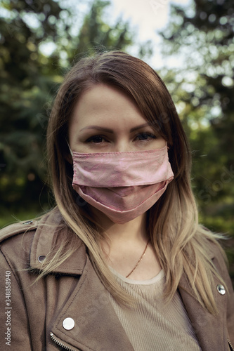 Portrait of a young girl in a protective medical mask in the park