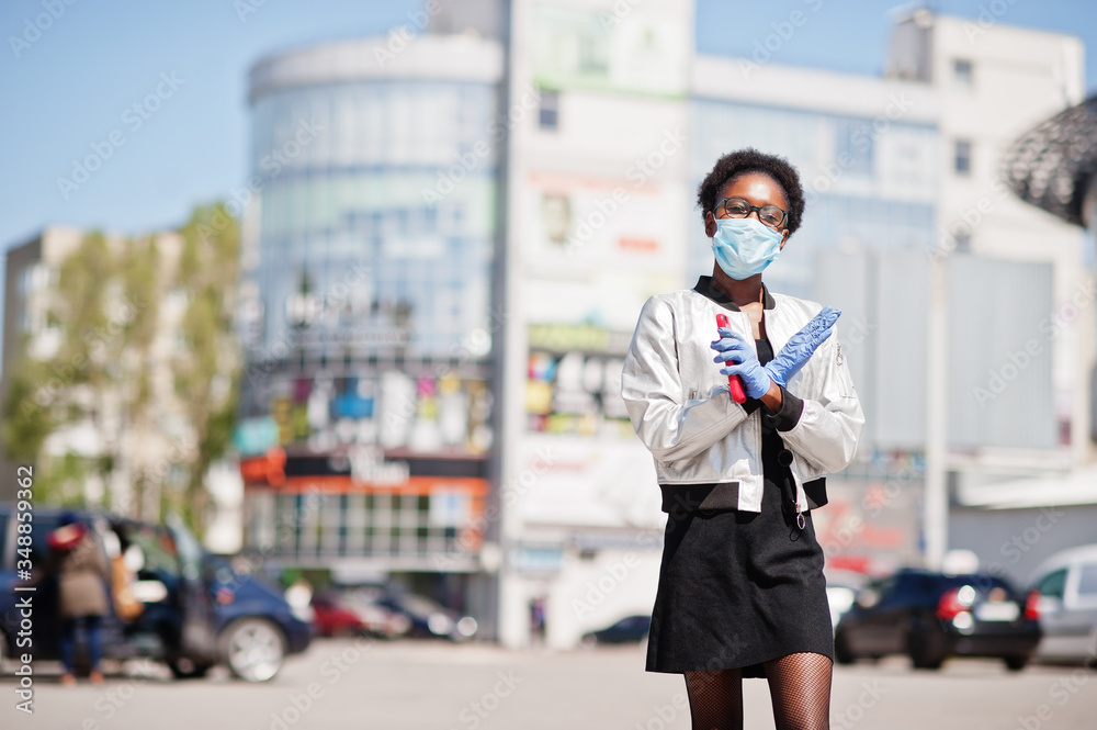 Fototapeta premium African woman wearing disposable medical mask and gloves walking outdoor during epidemic time.