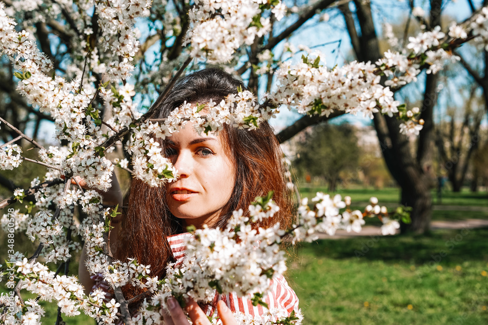 Portrait of a young girl with long hair walking in an Apple orchard in early spring, a blooming Apple tree with white flowers. Ecology, care Portrait of a young girl with long hair walking in an Apple orchard in early spring, a blooming Apple tree with white flowers. Ecology, care