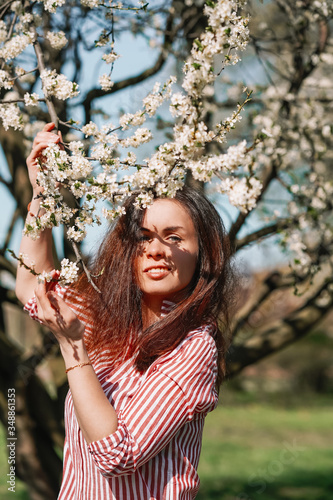 Portrait of a young girl with long hair walking in an Apple orchard in early spring, a blooming Apple tree with white flowers. Ecology, care
