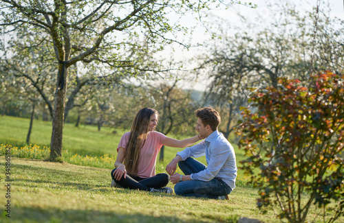 Young couple in german green landscape with trees and bushes, the girlfriend is stroking the boyfriend the cheek