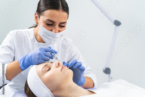 Dermatologist injecting a cheek filler to a woman