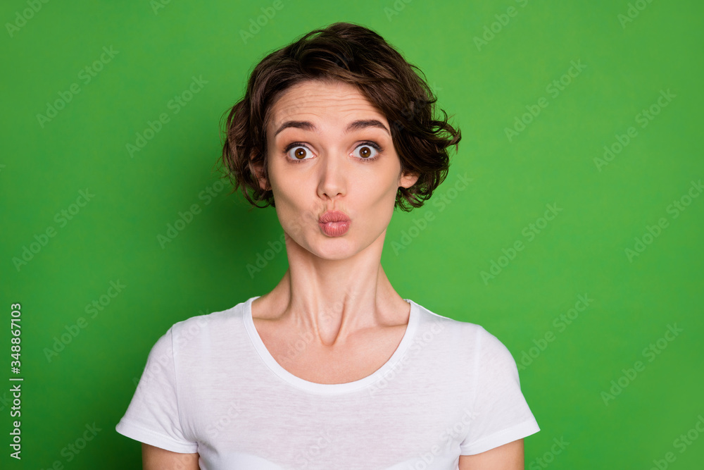 Closeup photo of cute attractive lady wavy bobbed short hairdo sending air kisses funny facial expression wear casual white t-shirt isolated bright green color background