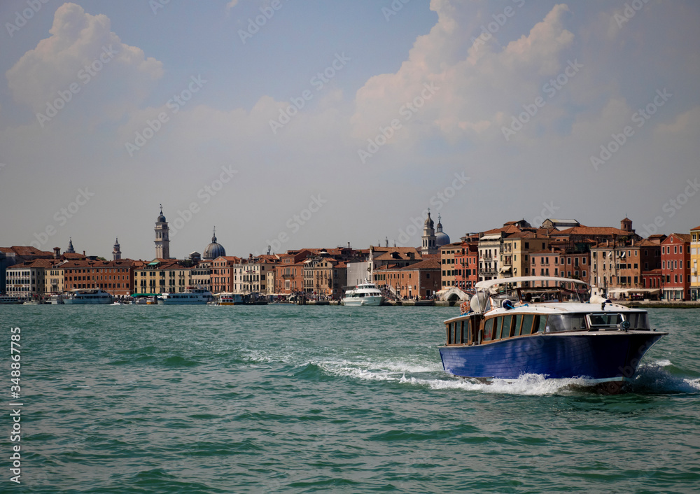 Obraz premium A view of Venice shore with a tourist ferry on the foreground on the late summer afternoon.