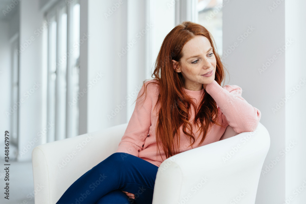 Young redhead woman relaxing in a comfy chair Young redhead woman relaxing in a comfy chair
