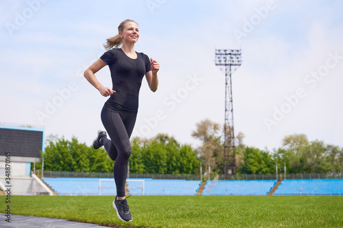Youn woman running on the stadium in full length
