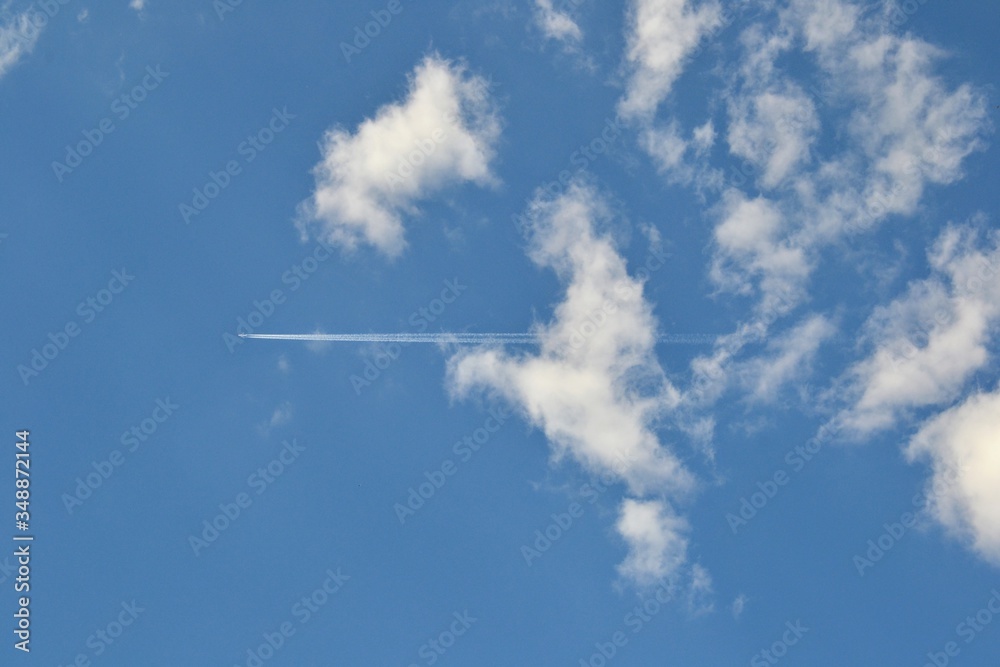 Trace of an airplane in the blue sky. Jet airplane leaves contrails (or vapor trails, traces) on blue sky background. Travel, holidays, vacation concept Trace of an airplane in the blue sky. Jet airplane leaves contrails (or vapor trails, traces) on blue sky background. Travel, holidays, vacation concept