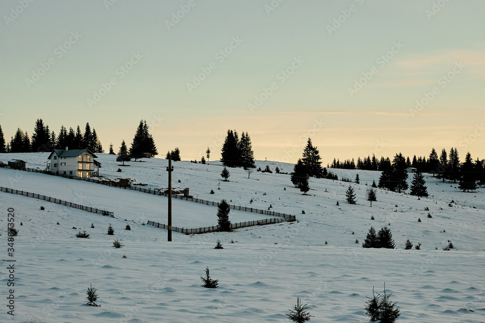 Winter morning during sunrise in the snowy Romanian countryside with some houses in the background. Winter morning during sunrise in the snowy Romanian countryside with some houses in the background.