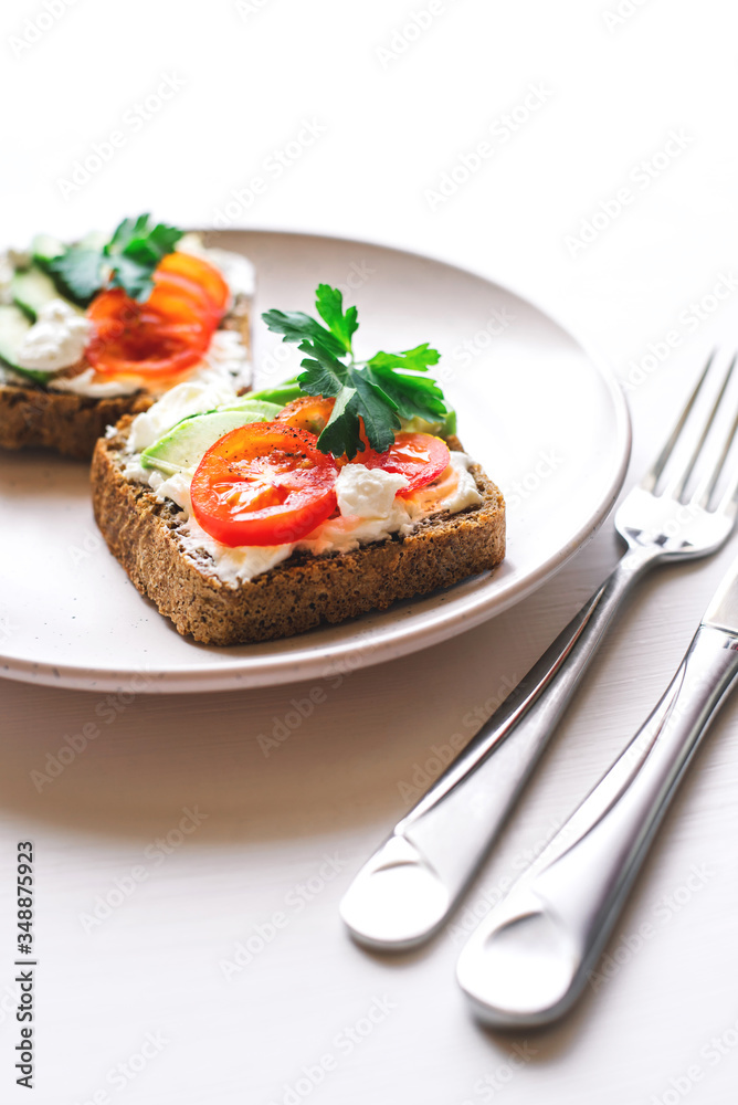 Avocado toast with cherry tomatoes and feta cheese on plate.