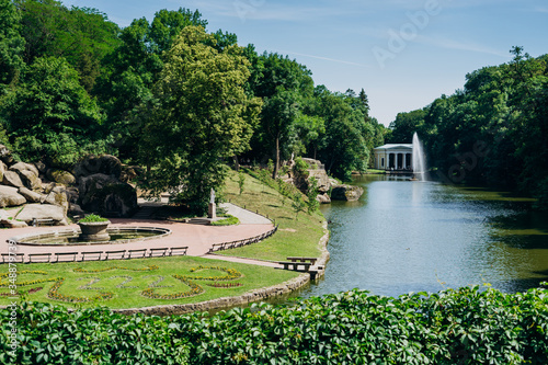 Sofia Park, Ukraine. Dendrological park in summer sunny day. Lake and fountain in a green park. Gazebo by the lake with a fountain.