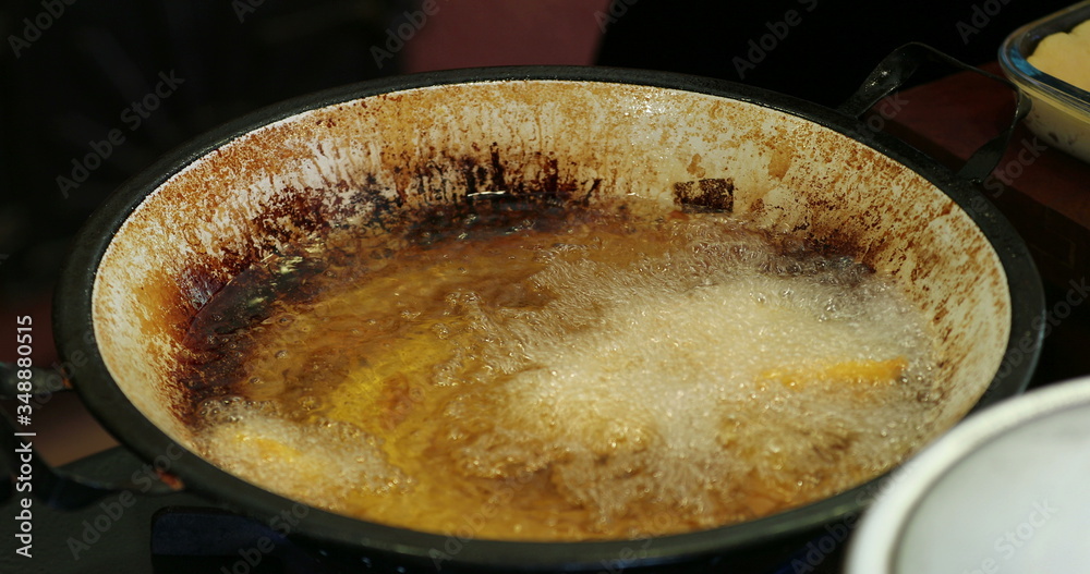 Frying food inside large boiling frying pan with oil