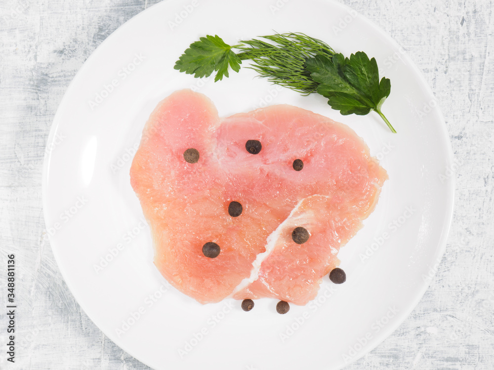 Sliced pieces of meat turkey game filet on white ceramic plate, allspice, cilantro, fennel on white ceramic plate on concrete background. Healthy eating concept Sliced pieces of meat turkey game filet on white ceramic plate, allspice, cilantro, fennel on white ceramic plate on concrete background. Healthy eating concept