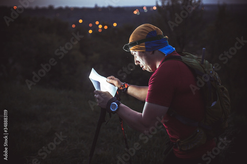 The guy during night orienteering shines a flashlight in a map of the area