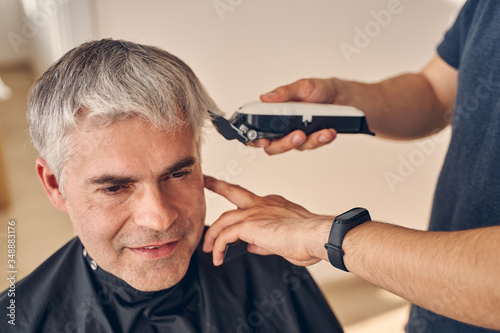Mature man getting hairdo with special equipment