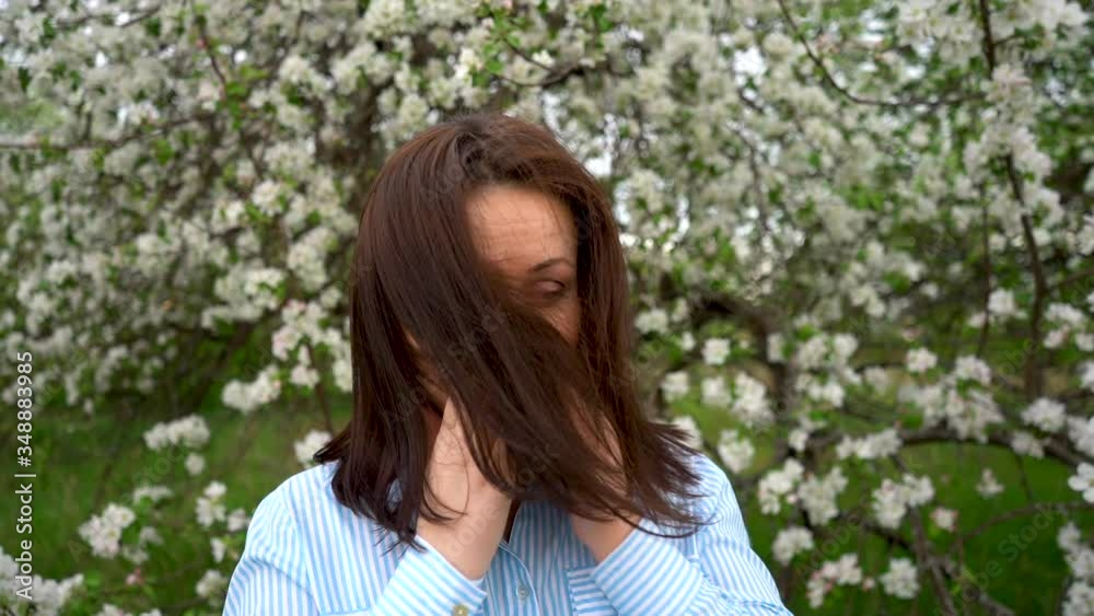 Girl sneezes, face close-up. Blooming trees in the background Girl sneezes, face close-up. Blooming trees in the background