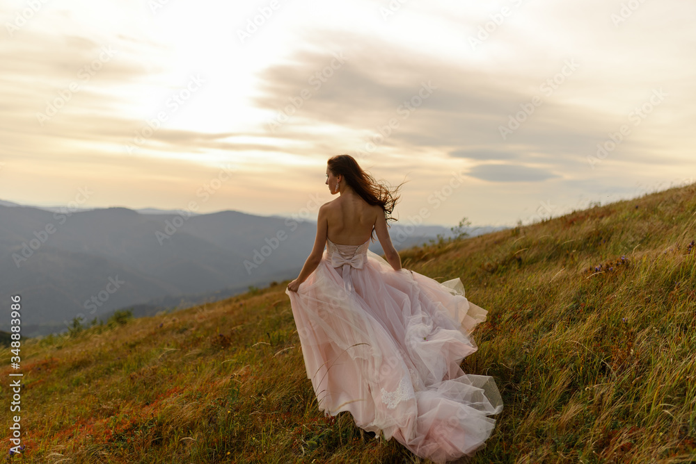 Portrait of a beautiful bride on a background of autumn mountains. A strong wind blows her hair and dress. Wedding ceremony on top of the mountain. Free space.