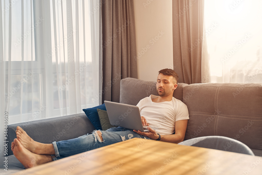 Handsome young male lying comfortably and working Handsome young male lying comfortably and working