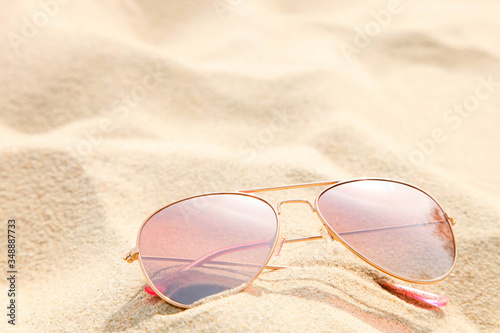 Pink sunglasses lie on the sea sand.