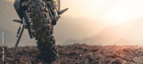 Fotografia Part of a motocross wheel on a mound, with sunrise