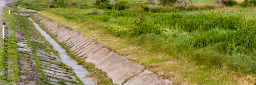 Gutter on the side of the road or with a ditch for water and a glade of green lawn along the road