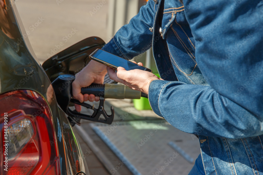 Obraz premium Tankowanie samochodu i płacenie za pomocą aplikacji na smartfonie.