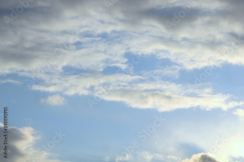 Clouds in the blue sky at sunset or dawn backlit by the sun. Place for text and design.