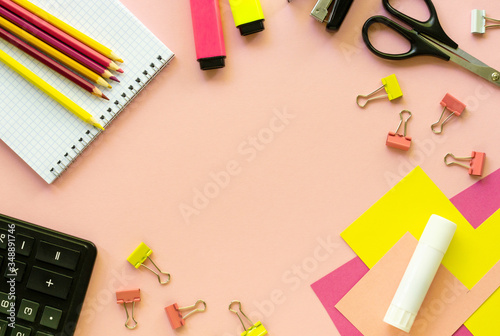 Various school and office supplies on a pink background
