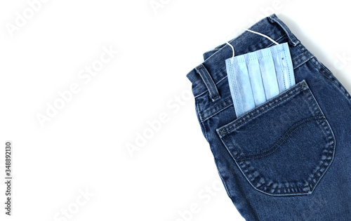 Classic blue jeans on the white background. Medical mask in the pocket. Pandemic concept. Copy space. Place for text and design. Top view. Flat layout
