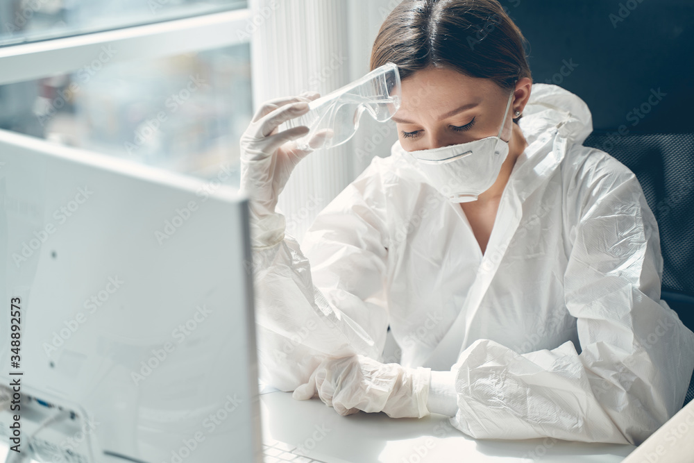 Naklejka premium Charming young woman in protective suit working in office