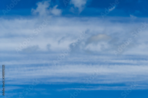 Blue sky with beautiful striped fluffy white clouds. The mood of happiness, love and delight. Great background for any design. Place for text and any items.