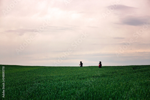 Pretenn children, boys, running in green field on a cloudy day