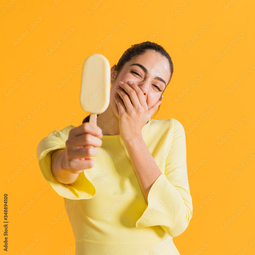 Happy woman with ice cream laughing covering mouth. Colorful creative yellow studio background. Happy woman with ice cream laughing covering mouth. Colorful creative yellow studio background.